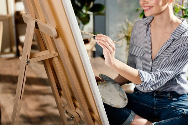 Imagen recortada de la joven artista pintura en caballete - foto de stock