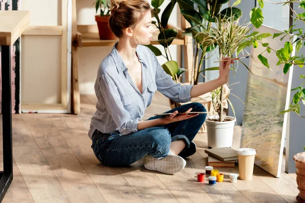 Vue latérale de l'artiste féminine dessinant sur toile en atelier — Photo de stock