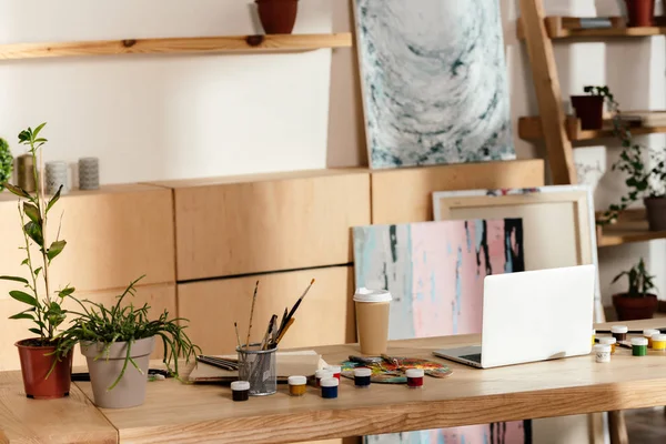 Interior do estúdio artista com materiais de pintura, laptop e plantas envasadas — Fotografia de Stock