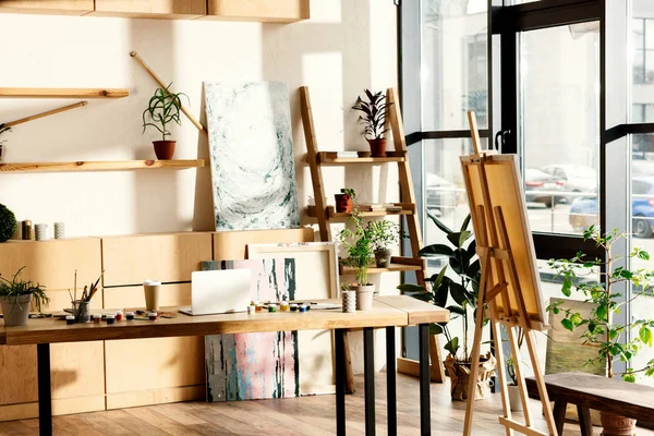 Interior do estúdio artista com materiais de pintura e laptop na mesa — Fotografia de Stock