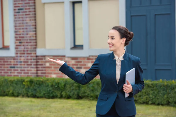 Hermosa mujer de negocios mostrando algo y mirando hacia otro lado - foto de stock