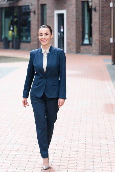 Beautiful businesswoman walking on street and looking away — Stock Photo
