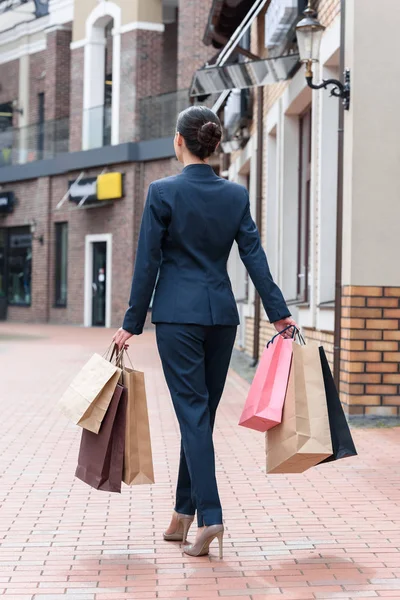 Visão traseira de empresária andando com sacos de compras na rua — Fotografia de Stock