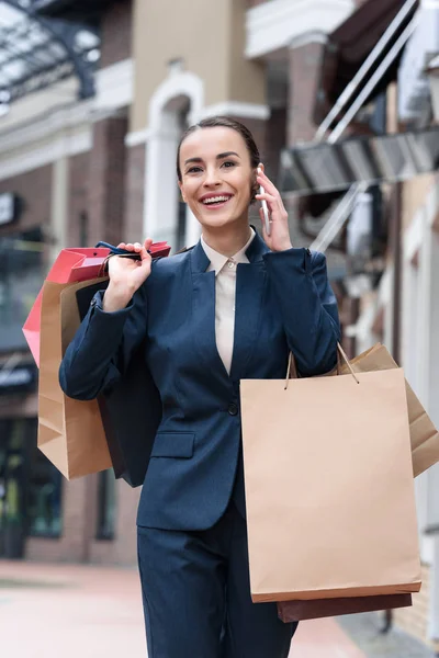 Atractiva mujer de negocios caminando de compras y hablando por teléfono inteligente - foto de stock