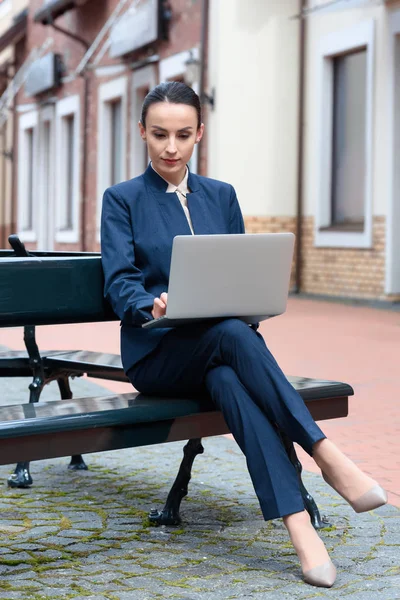 Hermosa mujer de negocios utilizando el ordenador portátil en el banco de la ciudad - foto de stock