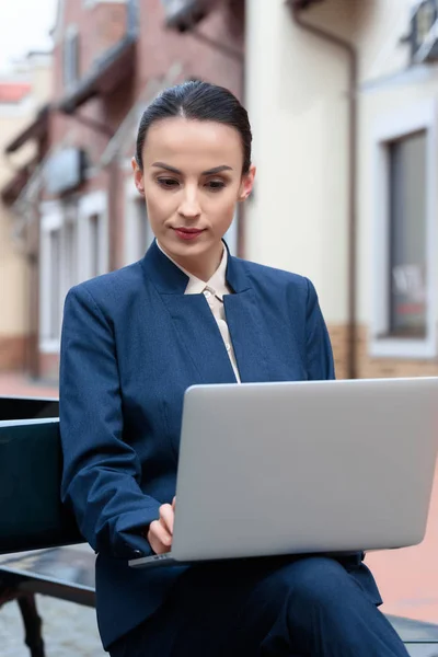 Hermosa mujer de negocios utilizando el ordenador portátil en el banco - foto de stock