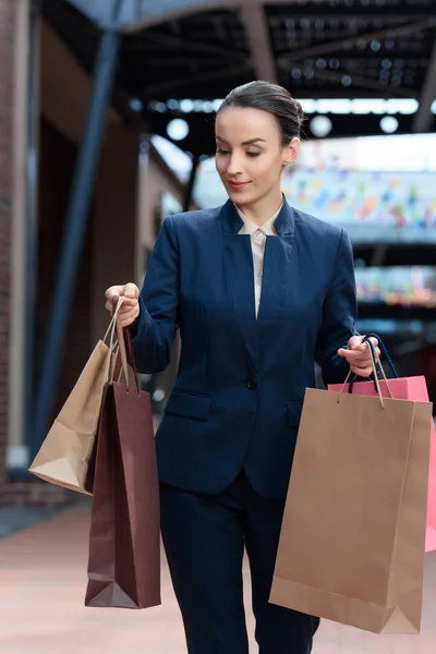 Atractiva mujer de negocios mirando bolsas de compras en las manos - foto de stock