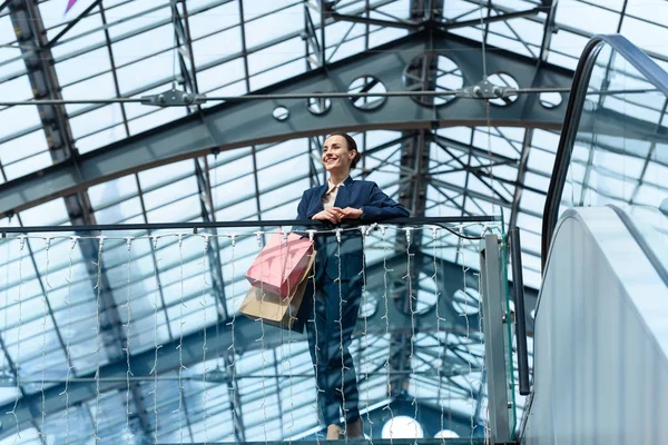 Vista basso angolo di attraente donna d'affari appoggiata su ringhiera nel centro commerciale — Foto stock