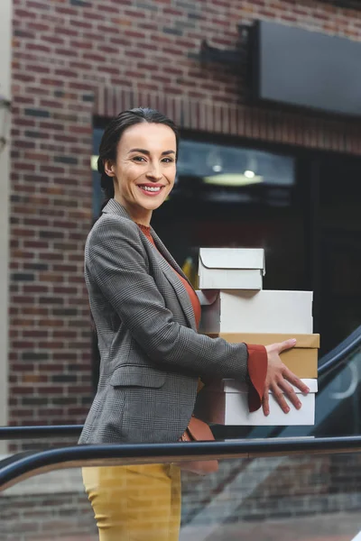 Souriant femme attrayante tenant des boîtes à provisions et regardant la caméra — Photo de stock