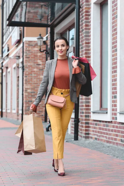 Mulher atraente andando com sacos de compras no ombro — Fotografia de Stock