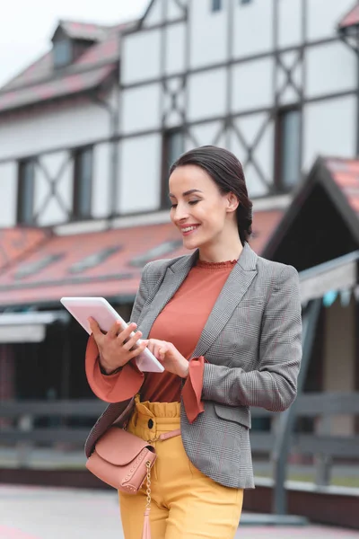 Beautiful stylish woman using tablet in city — Stock Photo