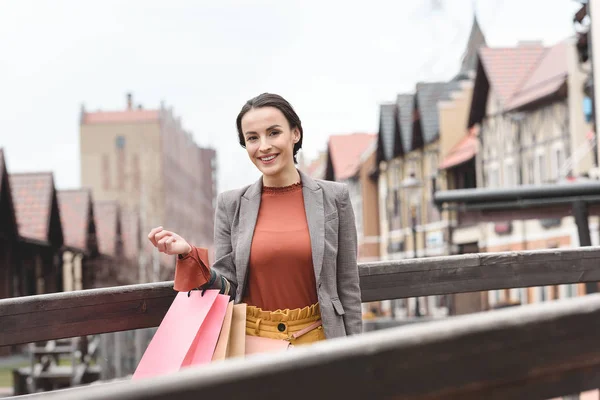 Attractive woman standing with shopping bags on bridge — Stock Photo