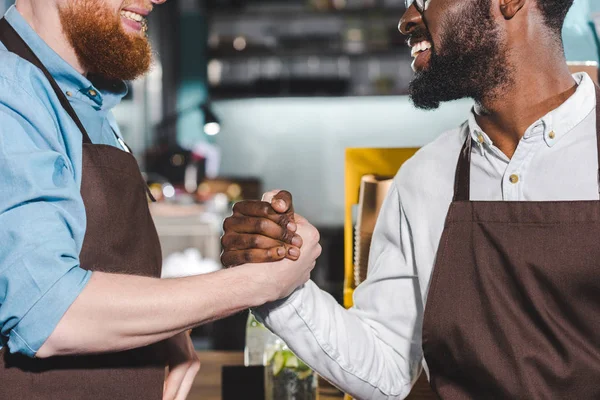 Cropped image of two smiling owners of coffee shop shaking hands — Stock Photo