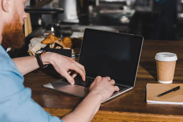 Abgeschnittenes Bild eines jungen männlichen Baristas, der mit Laptop am Tisch sitzt — Stockfoto