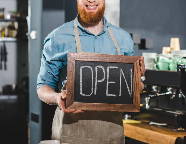 Immagine ritagliata di giovane barista maschio che tiene la lavagna con scritte aperte in caffetteria — Foto stock