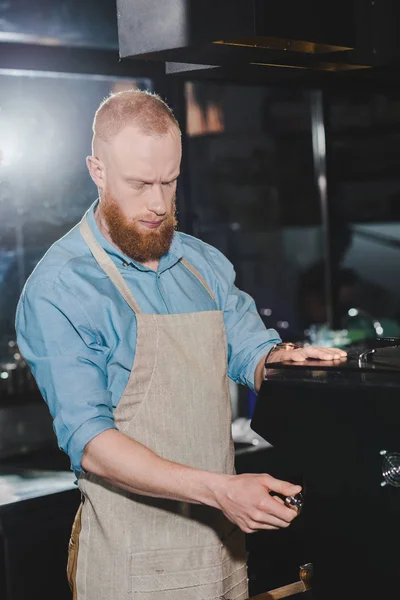 Jeune homme barista dans tablier en utilisant la machine à café — Photo de stock