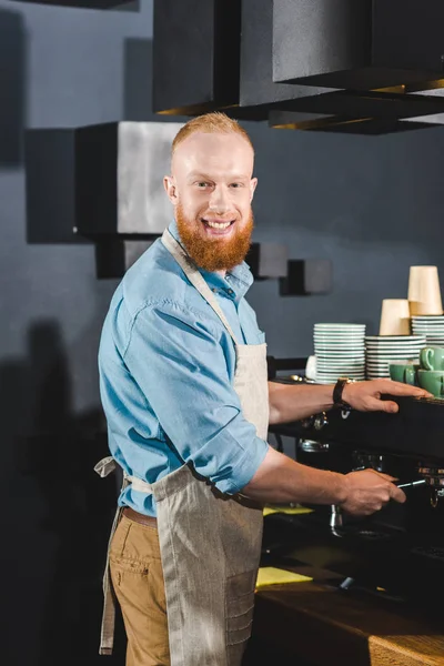Smiling young male barista doing coffee on machine in coffee shop — Stock Photo