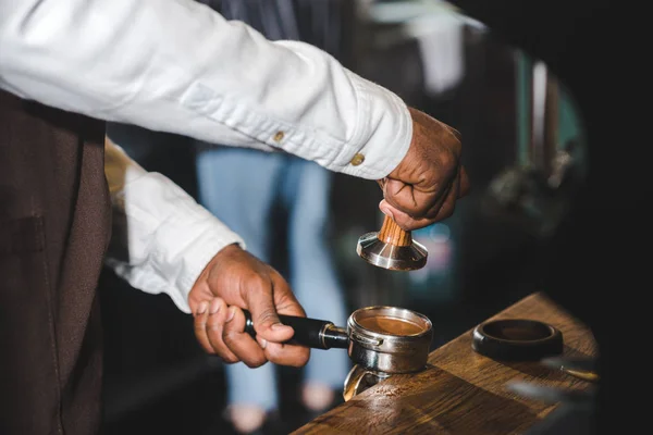 Cropped shot of african american barista in apron making coffee in cafe — Stock Photo