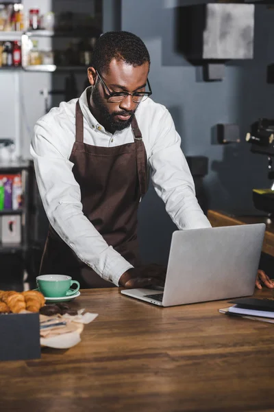 Junge afrikanisch-amerikanische Barista mit Laptop bei der Arbeit im Café — Stockfoto