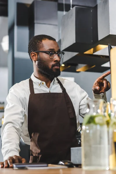 Bonito jovem africano americano barista em óculos que trabalham no café — Fotografia de Stock