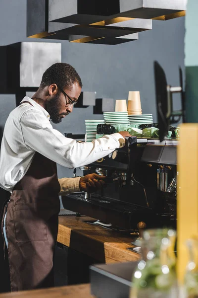 Side view of african american barista in eyeglasses working with coffee machine — Stock Photo