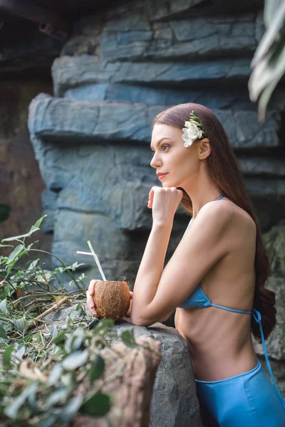 Stilvolles Mädchen posiert mit Kokoscocktail im tropischen Garten — Stockfoto