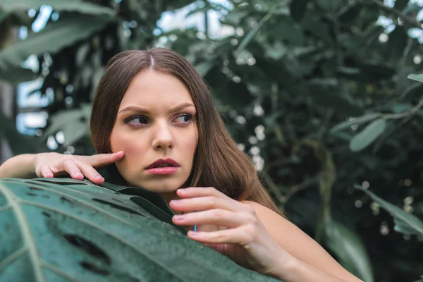 Attraktive Frau posiert im tropischen Garten in der Nähe von Monstera Blatt — Stockfoto