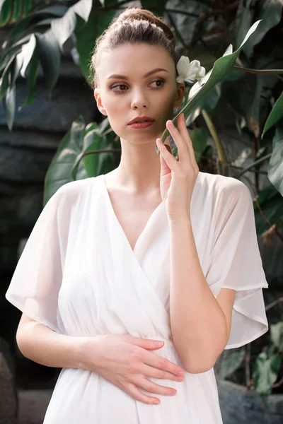 Chica atractiva posando en vestido blanco en jardín tropical - foto de stock