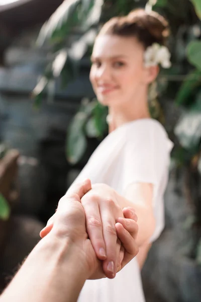 Messa a fuoco selettiva della donna in abito bianco tenendosi per mano con l'uomo — Foto stock