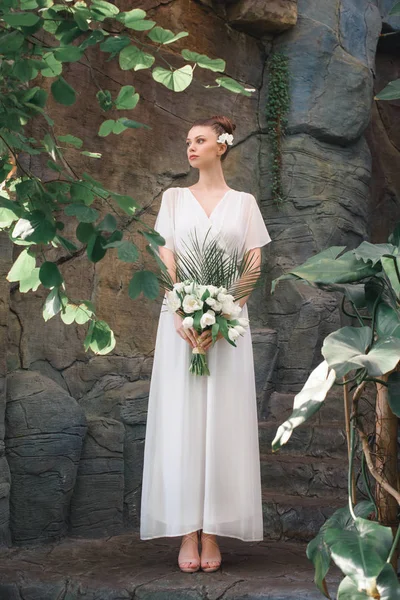 Красива наречена позує в білій сукні з весільним букетом — стокове фото