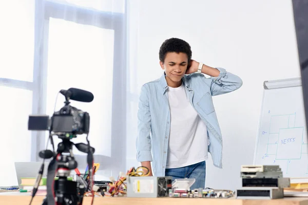 African american teenager shooting video blog and looking at table with technical equipment at home — Stock Photo