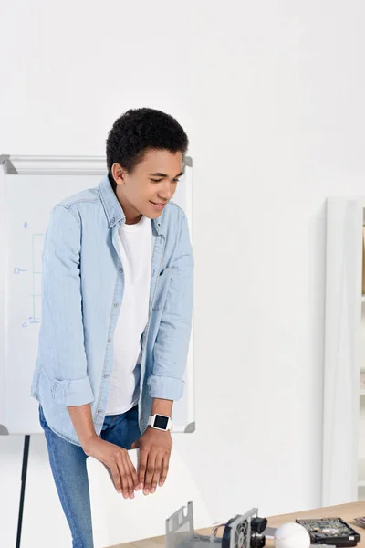 Africano americano adolescente guardando tavolo con attrezzatura tecnica a casa — Foto stock