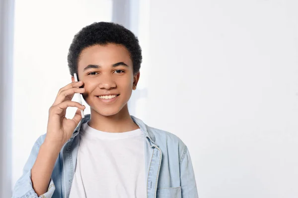 Sorridente adolescente afroamericano che parla con lo smartphone a casa — Foto stock