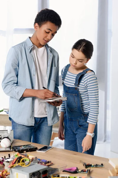 Multikulti-Freunde schauen zu Hause aufs Notizbuch — Stockfoto