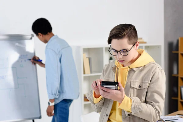 Chicos adolescentes multiculturales estudiando y mirando el circuito informático en casa - foto de stock