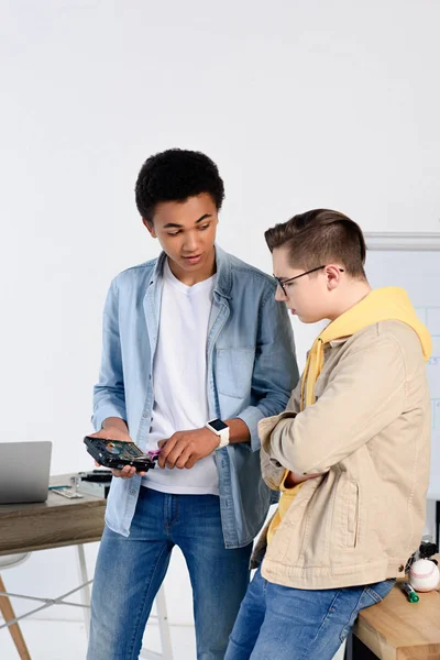 Multicultural teen boys looking at computer circuit at home — Stock Photo