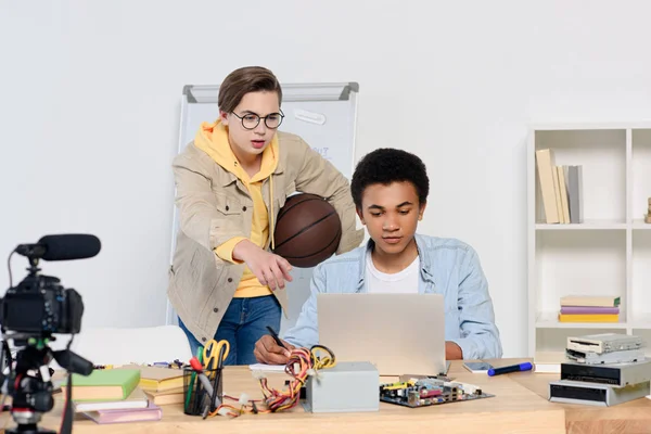 Adolescente caucasiano apontando em algo no laptop para amigo afro-americano em casa — Fotografia de Stock