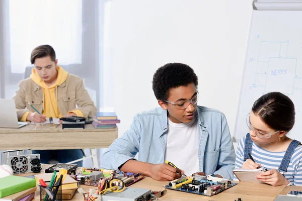 Adolescentes multiculturales que fijan la placa madre de la computadora en el país - foto de stock