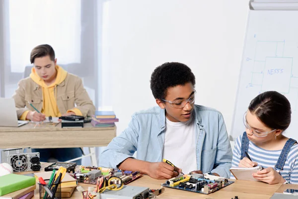 Multiculturale adolescenti fissaggio scheda madre del computer a casa — Foto stock