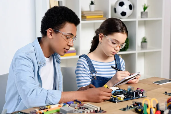 Amigos multiculturales estudiando juntos y probando el circuito informático en casa - foto de stock