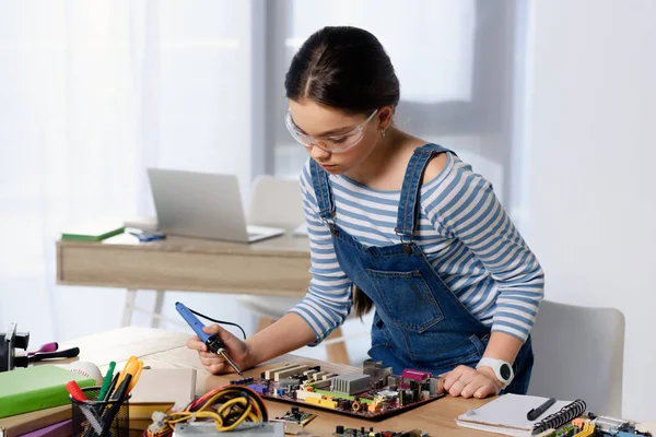 Adolescente fêmea computador de solda motherboard com ferro de solda em casa — Fotografia de Stock