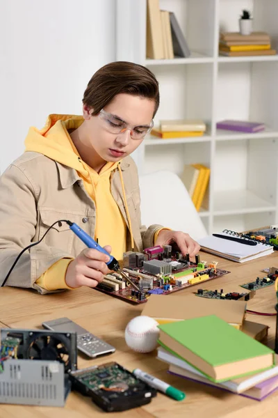 Teen boy soldering computer circuit with soldering iron at home — Stock Photo