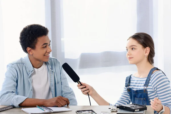 Caucásico adolescente niño realización de entrevista con africano americano amigo para vlog en casa - foto de stock