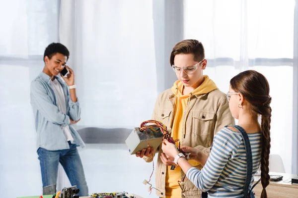 Adolescentes mirando la fuente de alimentación de la computadora en el hogar - foto de stock