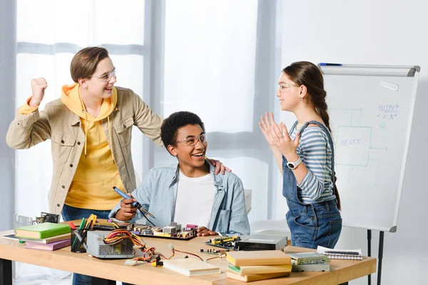 Adolescentes multiculturales felices mostrando sí gesto mientras que la ingeniería en casa - foto de stock