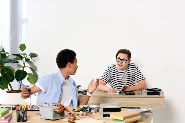 Adolescenti multiculturali che parlano mentre fissano la scheda madre del computer a casa — Foto stock