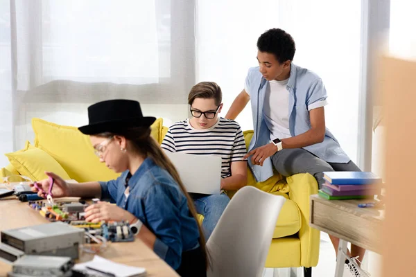 Adolescentes multiculturais estudando com laptop e placa-mãe de computador em casa — Fotografia de Stock