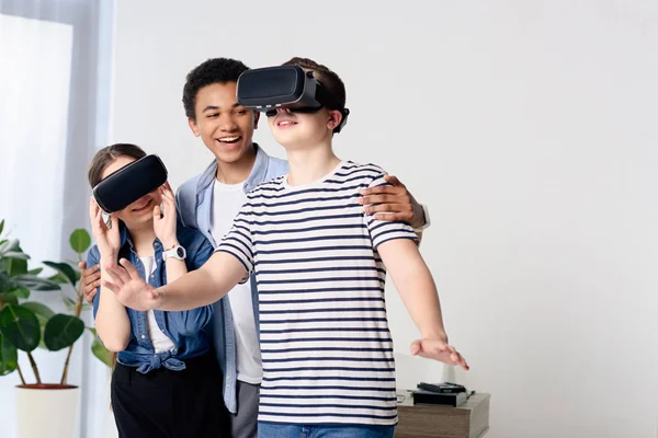 Adolescentes multiculturales que se divierten con auriculares de realidad virtual en casa - foto de stock