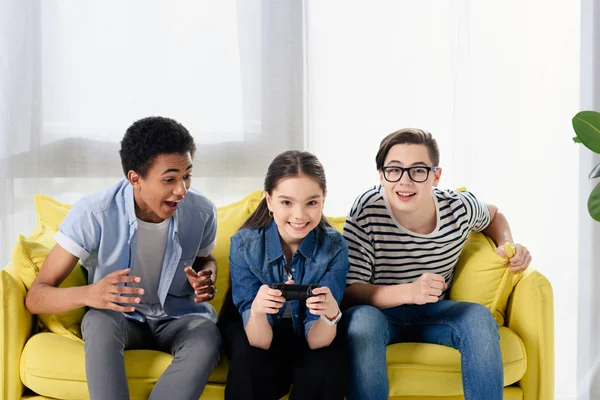 Multicultural teen boys supporting friend playing video game at home — Stock Photo