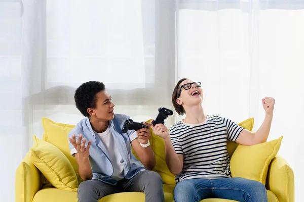 Multiculturel adolescent les garçons montrant oui gestes lors de la victoire jeu vidéo à la maison — Photo de stock